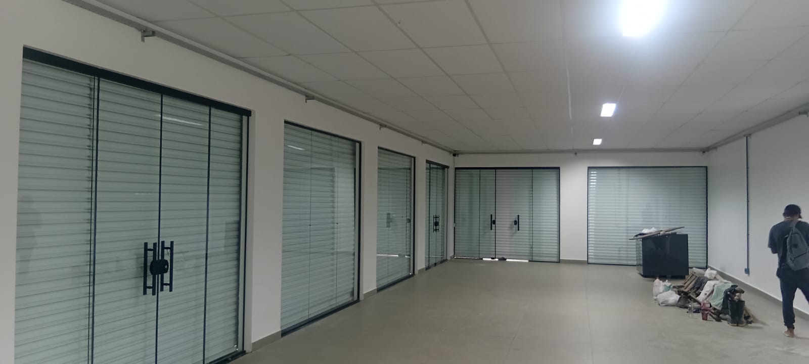 Escritório comercial com forro modular mineral e divisórias de vidro.