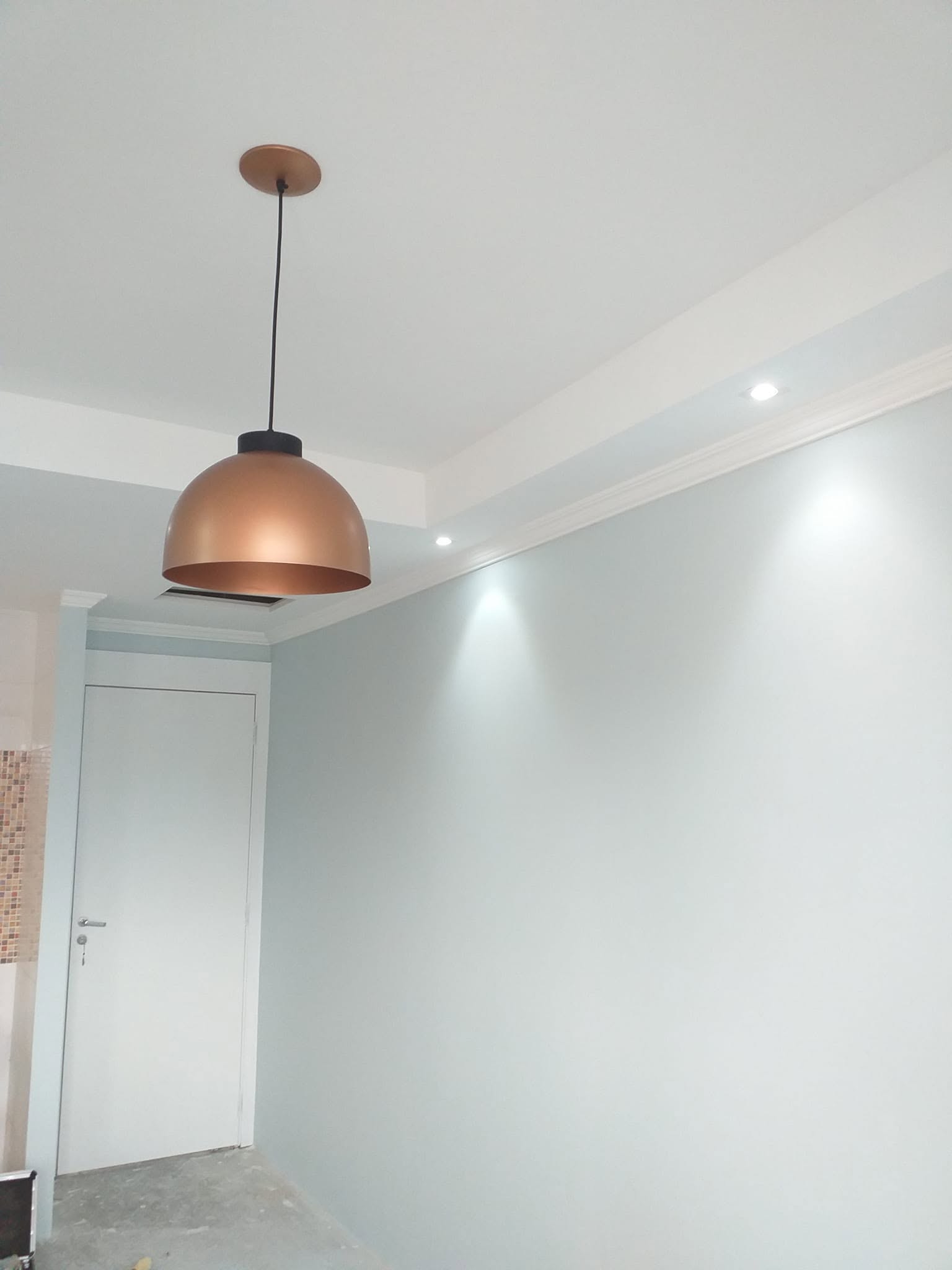 Detalhe de acabamento em moldura de gesso e instalação de luminária pendente.
