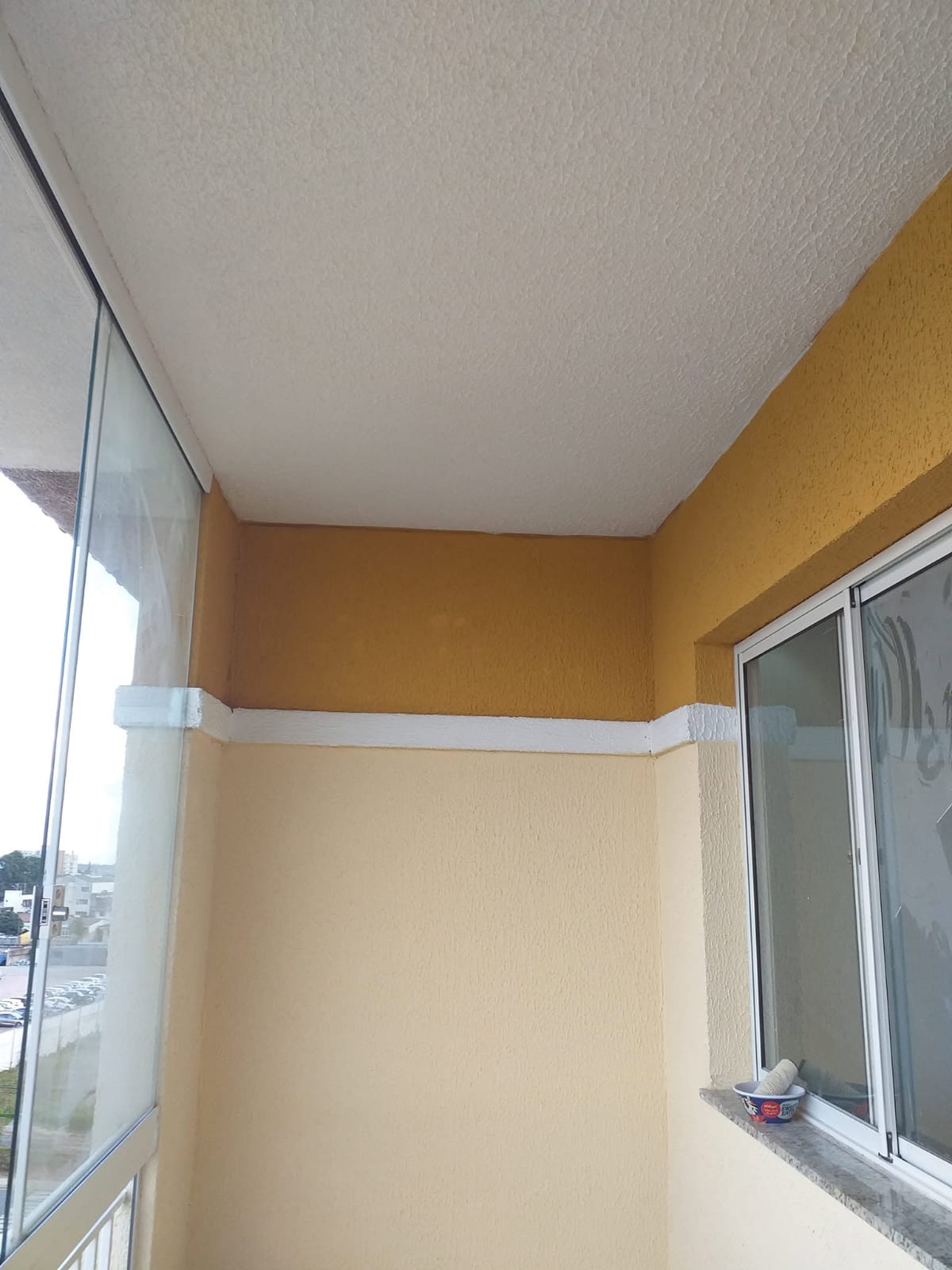Pintura decorativa em varanda residencial com aplicação de textura e cores contrastantes.